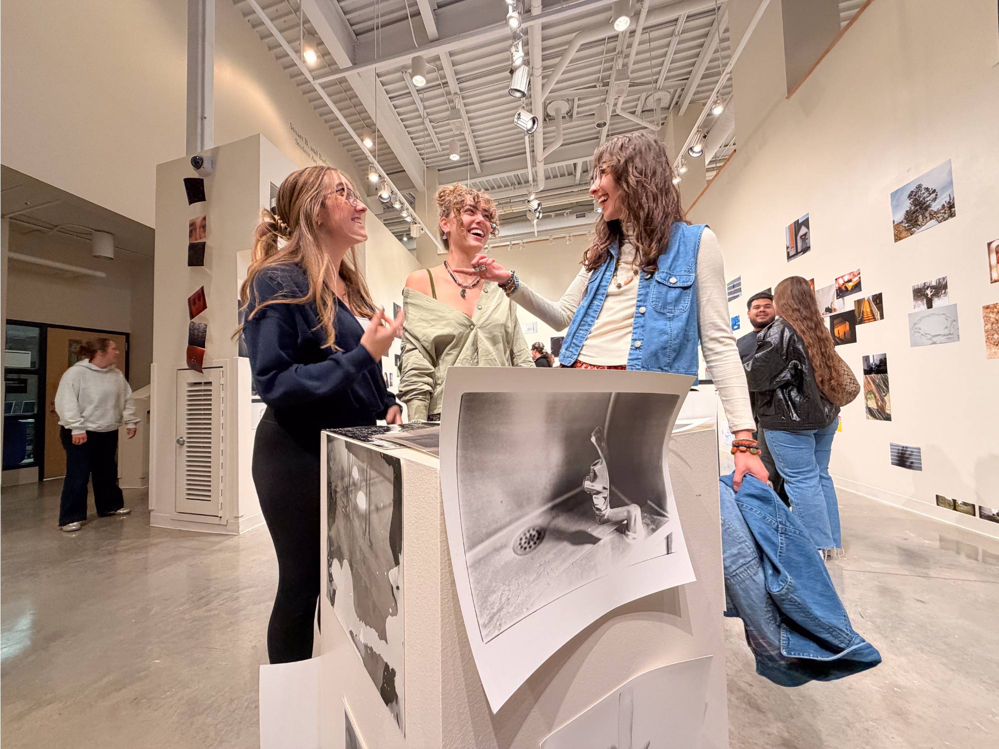 Attendees at a photography exhibition near a display of darkroom images